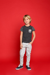 Full length portrait of cute little boy on red background