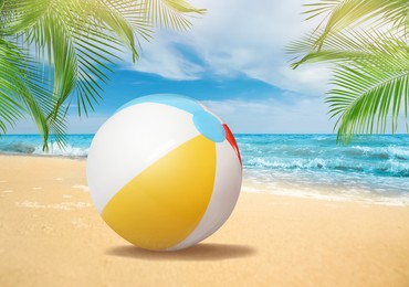 Colorful beach ball on sandy coast near sea