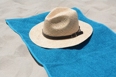 Soft blue towel and straw hat on sandy beach