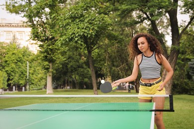 Young African-American woman playing ping pong outdoors