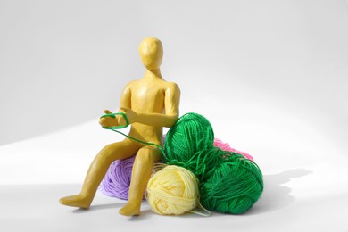 Human figure made of yellow plasticine knitting with color threads on white background
