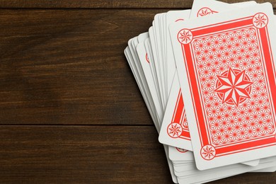Deck of playing cards on wooden table, top view. Space for text