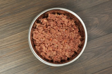 Wet pet food in feeding bowl on wooden background, top view