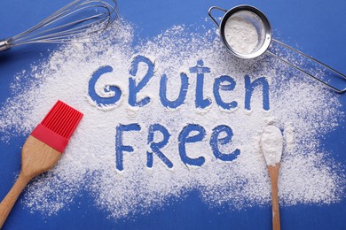 Kitchen utensils and phrase Gluten free written with flour on blue background, flat lay