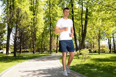 Young man on morning run in park, space for text. Fitness lifestyle