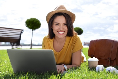 Photo of Beautiful woman using laptop on green lawn outdoors