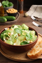 Photo of Delicious cucumber salad and toasted bread served on wooden table