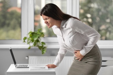 Young woman suffering from menstrual pain in office
