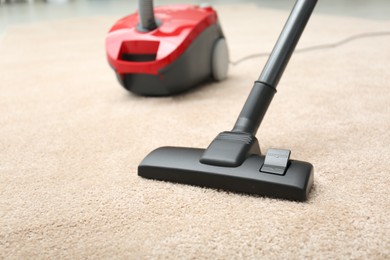 Photo of Removing dirt from carpet with modern vacuum cleaner indoors