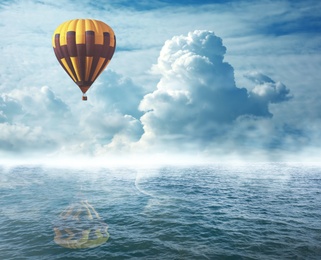 Dream world. Hot air balloon in cloudy sky over misty sea