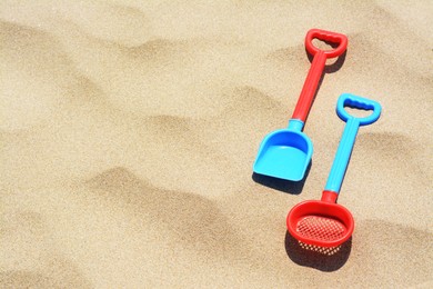 Plastic shovel and sieve on sand, space for text. Beach toys