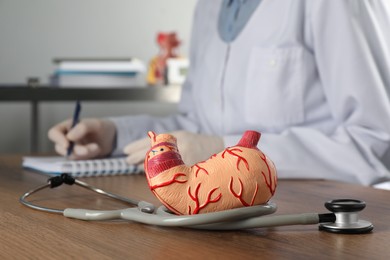 Human stomach model with stethoscope and gastroenterologist at table in clinic, closeup