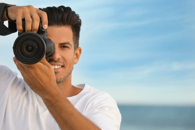 Photographer taking picture with professional camera near sea