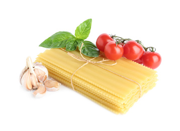 Uncooked lasagna sheets with cherry tomatoes, garlic and basil isolated on white