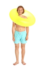 Attractive young man in swimwear with yellow inflatable ring on white background