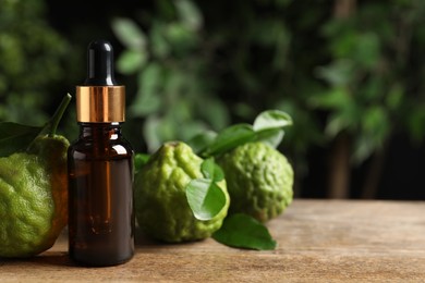 Glass bottle of bergamot essential oil and fresh fruits on wooden table. Space for text