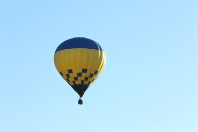 Colorful hot air balloon flying in blue sky. Space for text