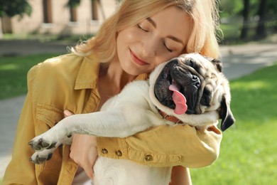 Woman with cute pug dog outdoors on sunny day. Animal adoption