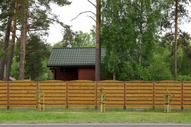 Modern building with green roof behind wooden fence on spring day
