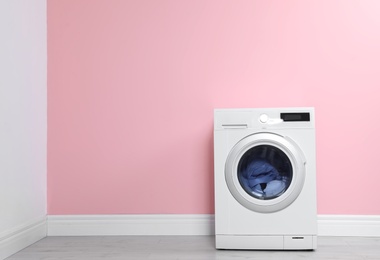 Washing machine with laundry near color wall. Space for text