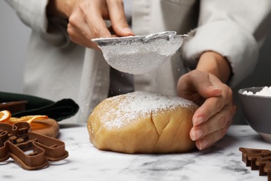 Photo of Woman flouring dough for cookies at white marble table, closeup