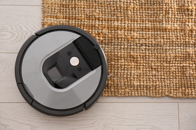 Modern robotic vacuum cleaner on brown rug, top view. Space for text