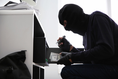 Thief taking money out of steel safe indoors