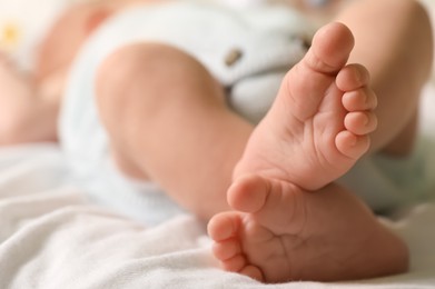 Cute newborn baby lying on bed, closeup of legs. Space for text