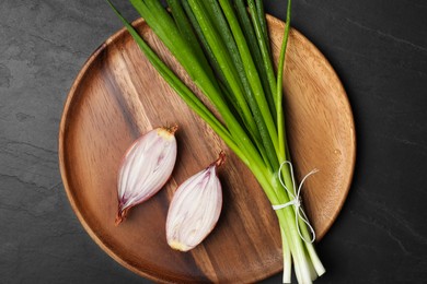 Bunch of fresh green onion and halved bulb on black table, top view