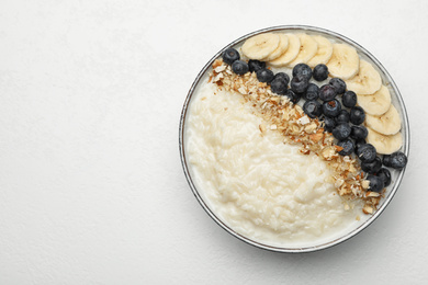 Delicious rice pudding with banana, blueberries and almond on light table, top view. Space for text
