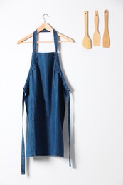 Denim apron and kitchen tools on light wall