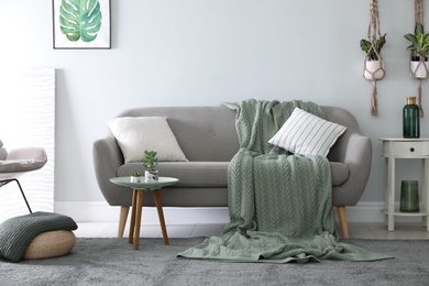 Soft knitted blanket on sofa in room. Home interior