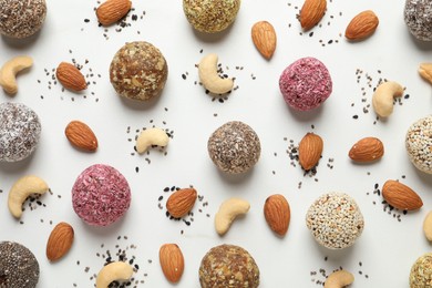 Delicious vegan candy balls and nuts on white table, flat lay