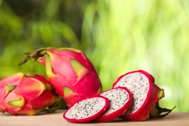 Photo of Delicious cut and whole dragon fruits (pitahaya) on wooden table