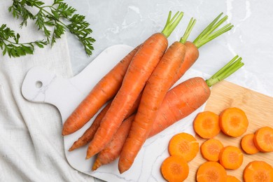 Whole and sliced fresh ripe juicy carrots on light grey marble table, flat lay