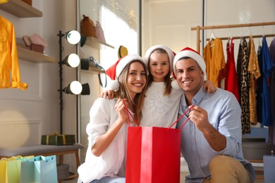 Happy family with Santa hats doing Christmas shopping in store