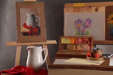 Artist's workplace with drawings, soft pastels and color pencils on table