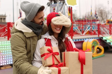 Lovely couple with Christmas presents in amusement park