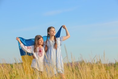 Happy girls with national flag of Ukraine in field. Space for text
