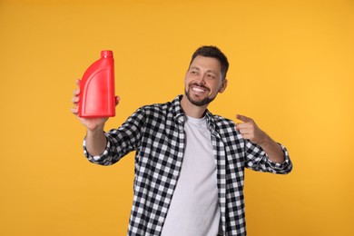 Man pointing at red container of motor oil on orange background