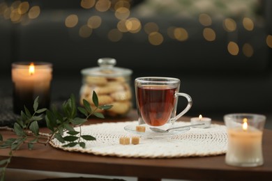 Photo of Tea, cookies and decorative elements on wooden table against blurred lights indoors