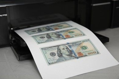Printing dollar banknotes on grey table, closeup. Fake money concept