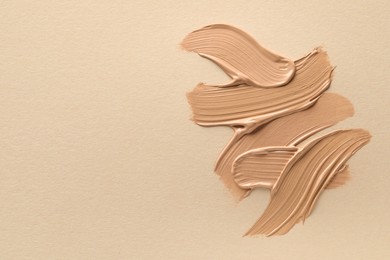 Samples of liquid skin foundations on beige background, top view. Space for text