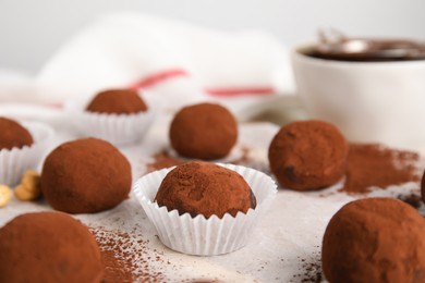 Delicious chocolate truffles powdered with cocoa on table, closeup