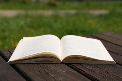 Photo of Open book on wooden table in park