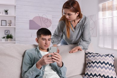Mother scolding her son while he using smartphone at home. Teenager problems