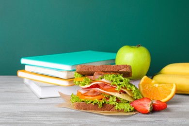 Photo of Tasty healthy food and different stationery on wooden table near green chalkboard, space for text. School lunch