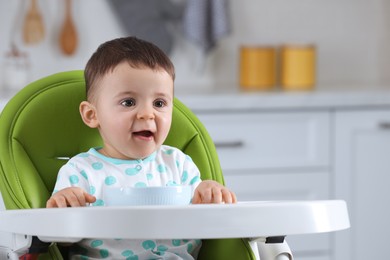 Cute little baby eating healthy food in high chair at home, space for text