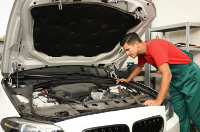 Photo of Professional mechanic checking modern car at automobile repair shop