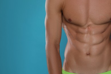 Shirtless man with slim body on light blue background, closeup. Space for text